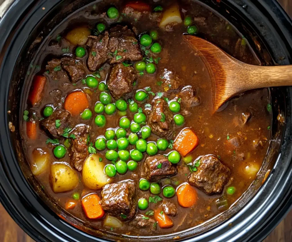 Frozen peas being added to slow cooker beef stew