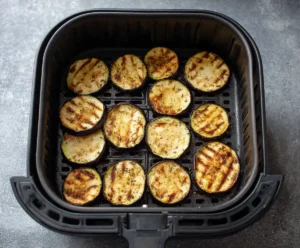 Breaded eggplant slices cooking in air fryer basket until crispy