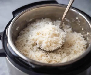 Fluffy cooked rice being fluffed with a fork in Instant Pot