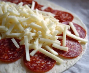 Mozzarella and pepperoni on tortilla for homemade pizza roll filling