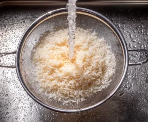 Rinsing white rice in strainer before making rice pudding with raisins