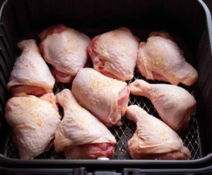 Seasoned chicken arranged in air fryer basket before cooking