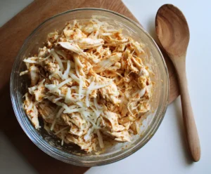 Shredded chicken mixed with cheese and enchilada sauce for enchilada filling