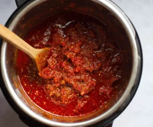 Tomato sauce and Italian seasoning stirred with beef in Instant Pot